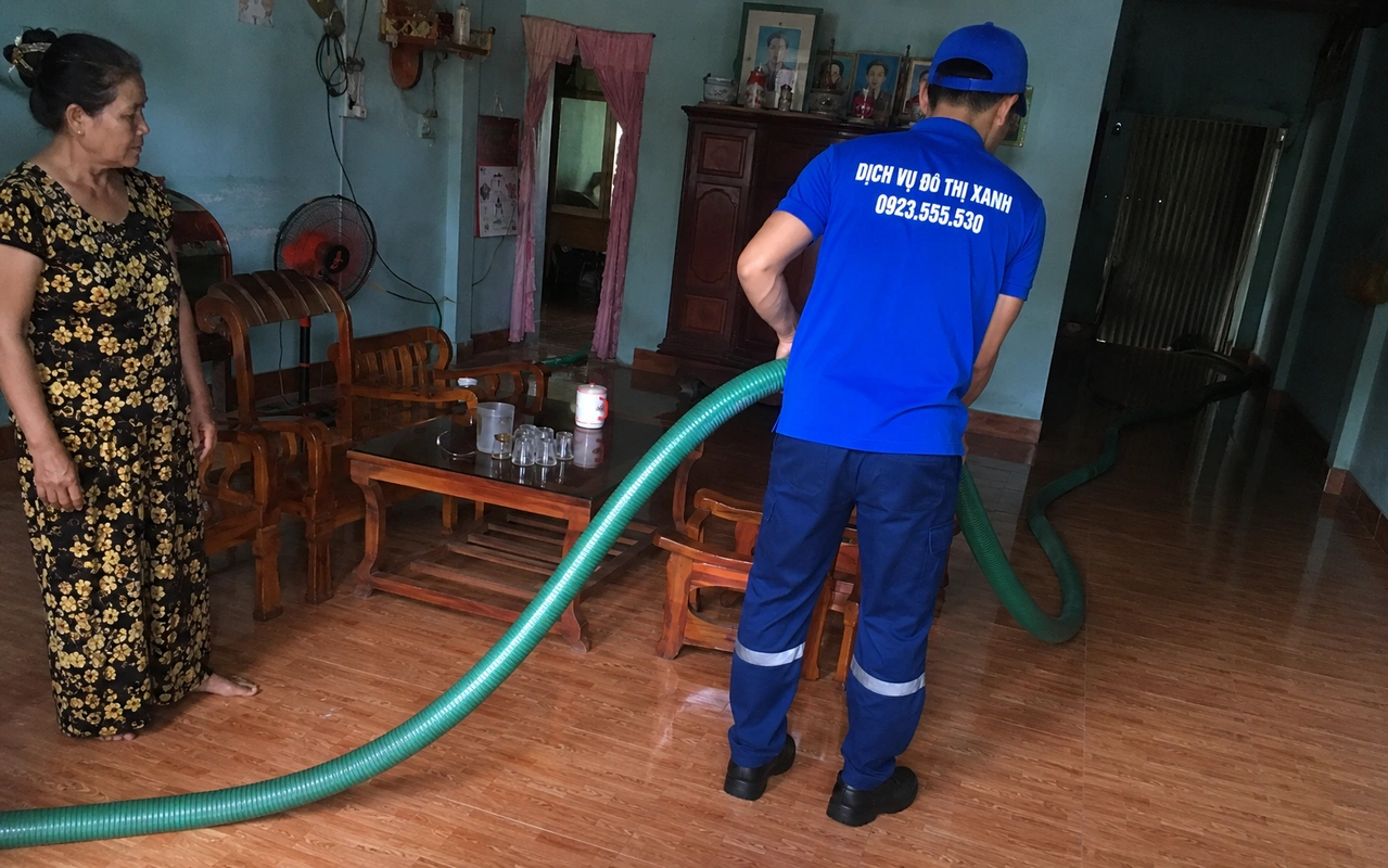 Nhân viên đưa ống hút hầm cầu qua phòng trong nhà