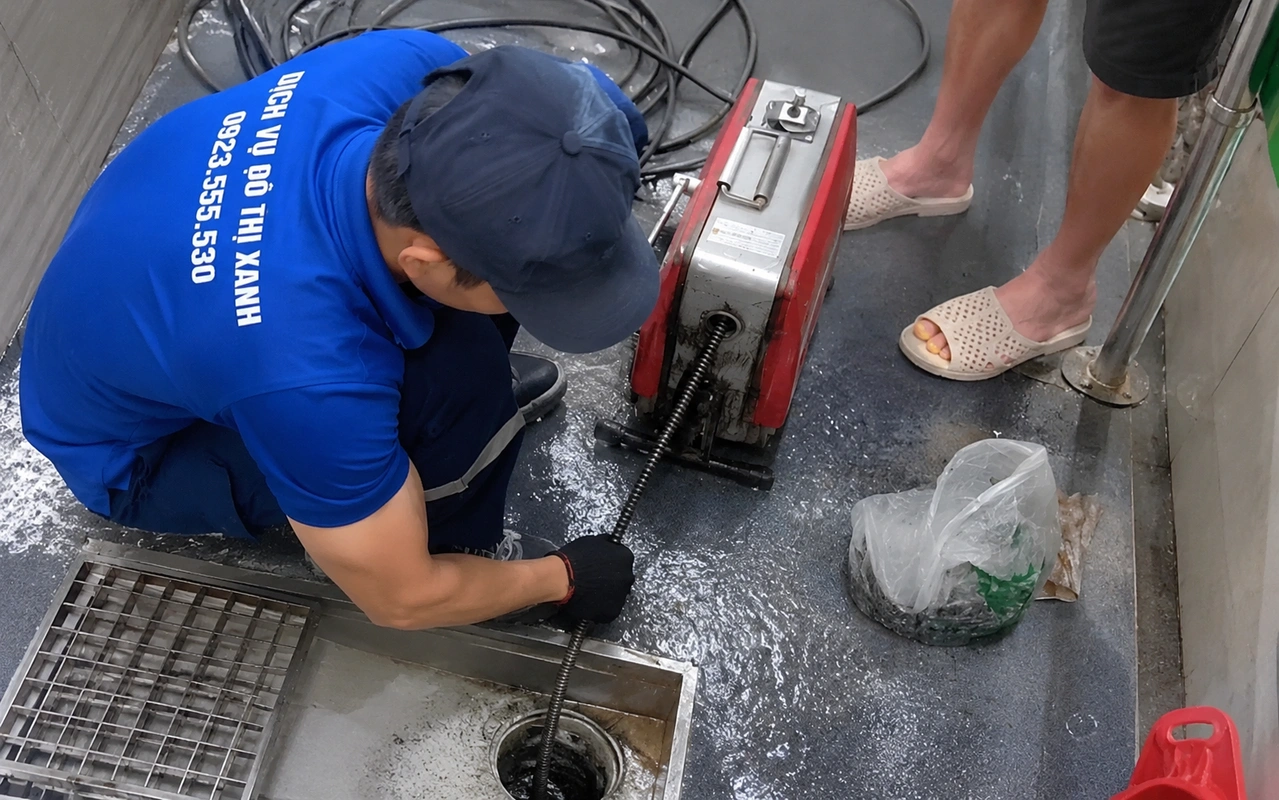Nhân viên đưa dây lò xo vào miệng thoát sàn để thông cống nghẹt