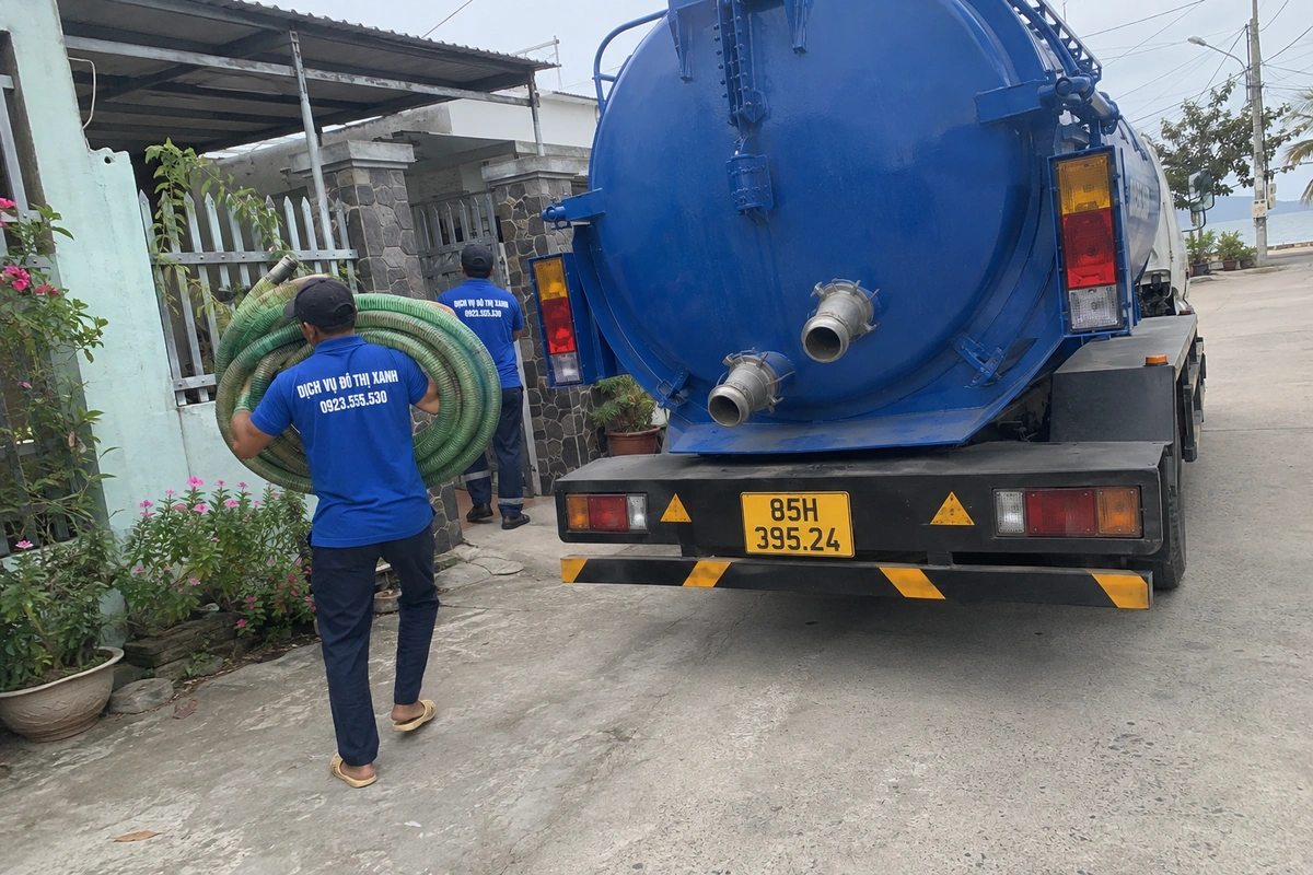 Nhân viên mang cuộn ống hút bên xe bồn