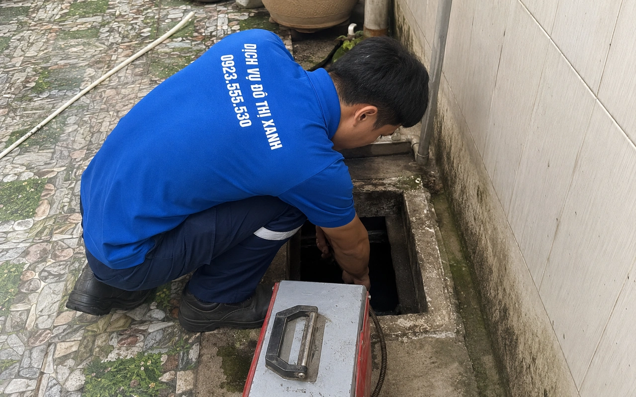 Nhân viên thông cống qua hố ga ngoài sân